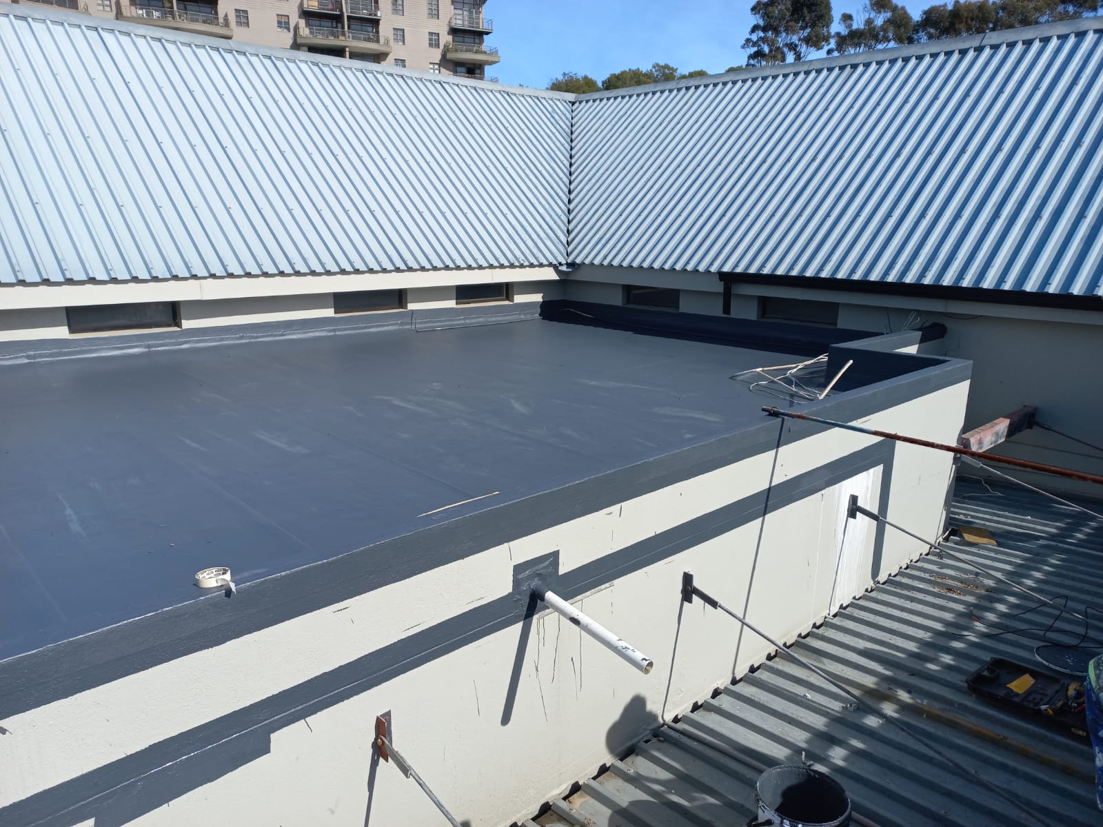 Commercial flat roof finished in grey membrane, turned up into the upstands