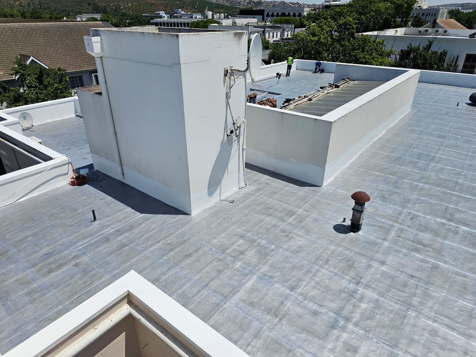 Concrete roof deck coated in white, with parapets and penetrations sealed