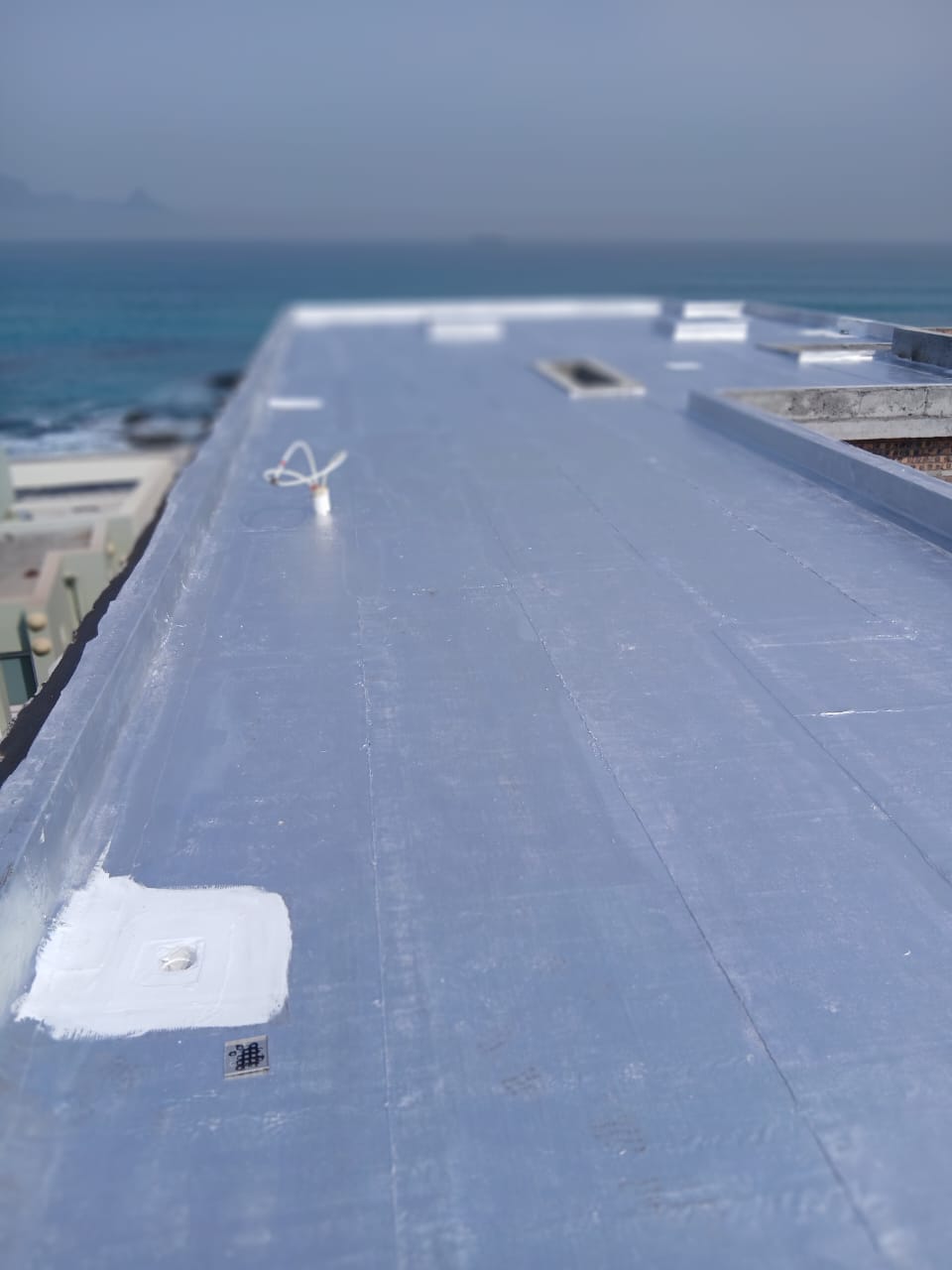 Outlet and fixing points sealed into a finished flat roof membrane running down to the sea