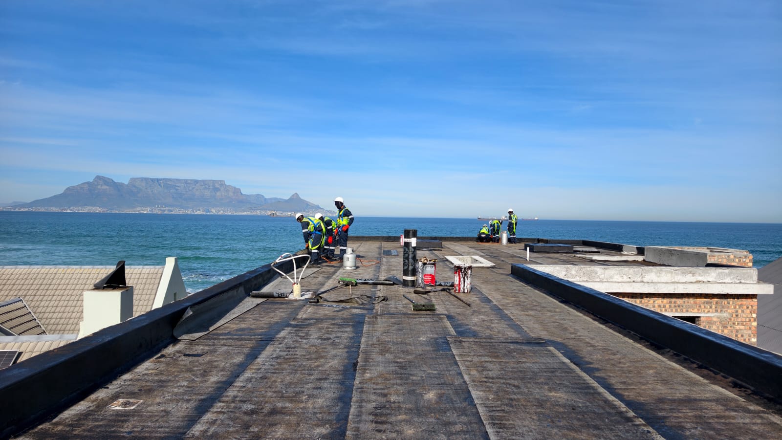 Flat roof deck prepared for membrane, gas bottles and rolls staged along the middle
