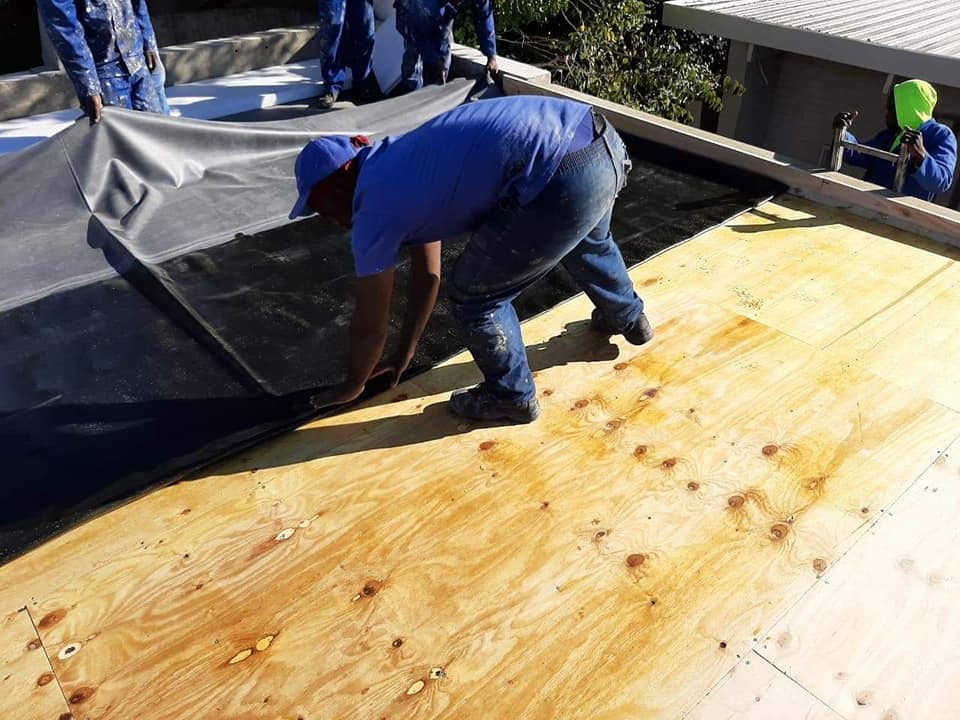Crew rolling out membrane over a newly boarded deck
