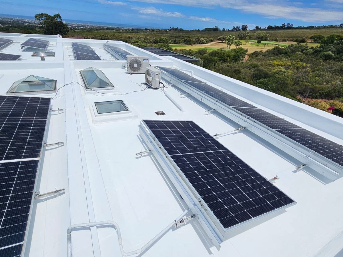 White waterproofing membrane on a flat roof carrying solar panels and skylights