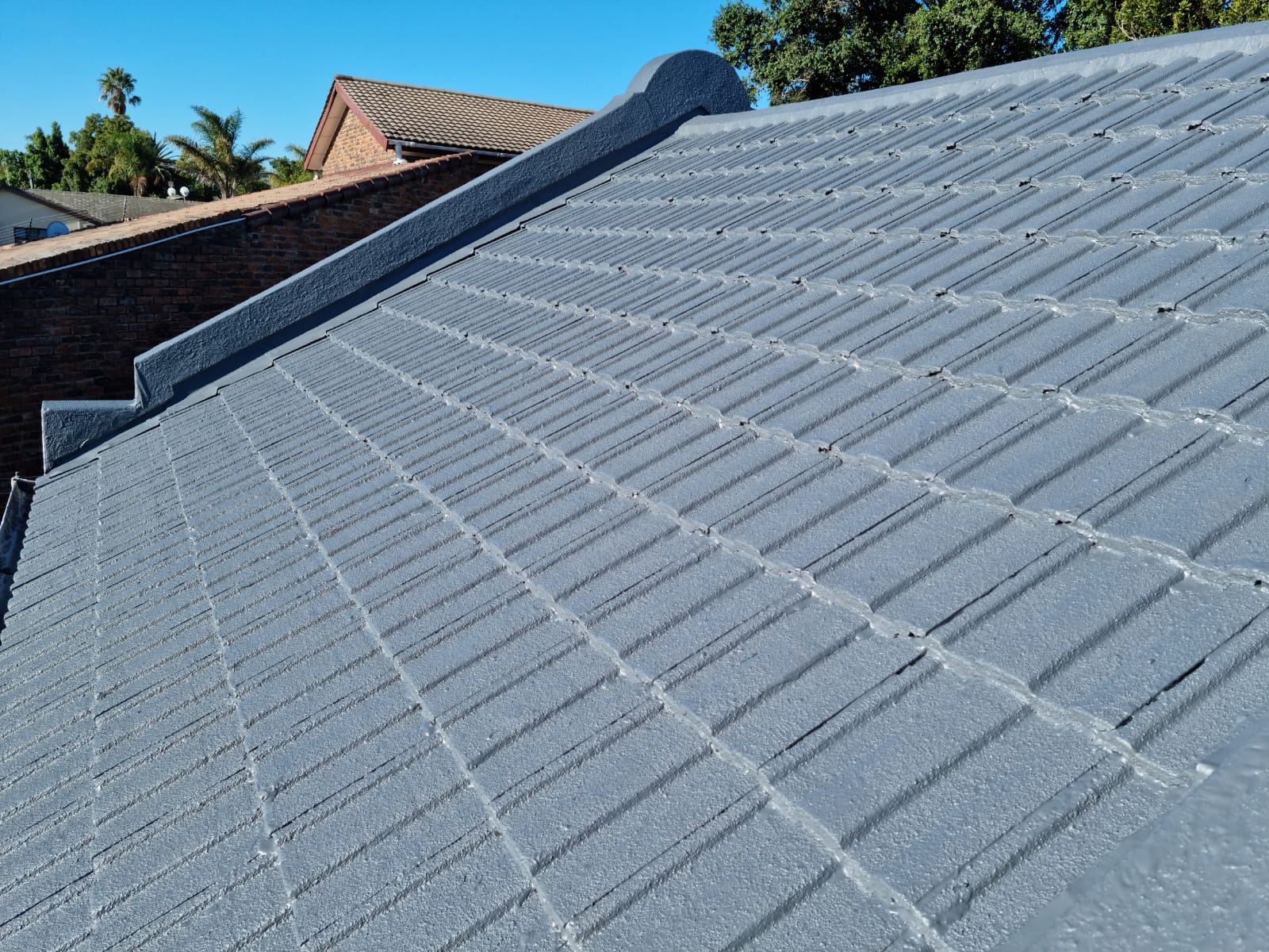 Concrete tiled roof coated in grey, with the ridge capping sealed