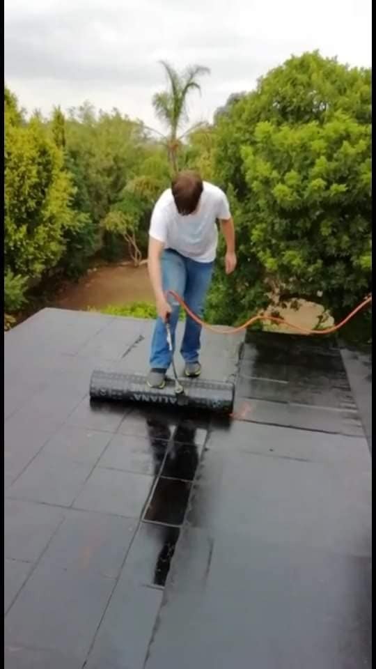 Bitumen membrane roll being bonded to a flat roof with a gas torch